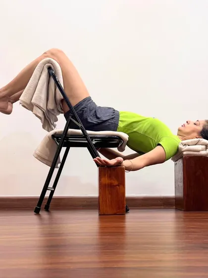 Viparita Karani, or legs-up-the-wall pose, is shown here with props for chronic fatigue. The chair and blocks support the body in a gentle inversion, which calms the nervous system and helps awaken latent energy for recuperation. This is a key restorative pose in the Iyengar method.