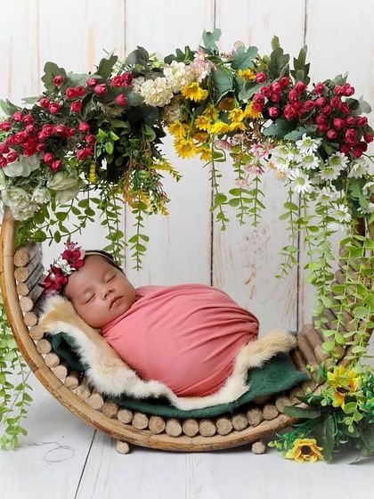 This beautiful crescent-shaped wooden prop, decorated with a cascade of flowers, is a favorite for creating enchanting, garden-themed newborn portraits.