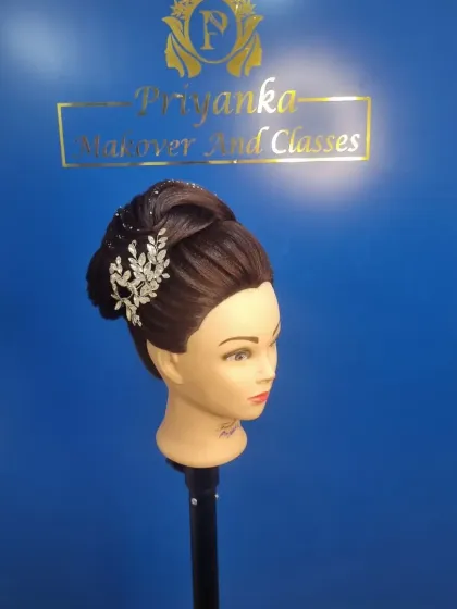 A side view of an intricate bridal bun practiced on a mannequin, showing the clean lines and placement of the hair accessory.