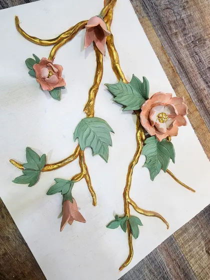 A detailed sample board showing sculpted branches with a gold finish, soft pink flowers, and green leaves. This helps clients visualize the final colors, textures, and materials together.