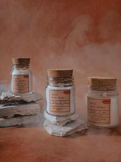 The "Coffee Smoke Arabica" candle is a dream for coffee lovers. I created this scent to capture the rich, smoky aroma of freshly roasted coffee beans. The candles are hand-poured in these simple, rustic jars with cork lids.