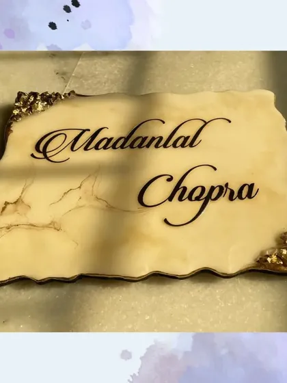 Adding a touch of elegance with this stunning resin nameplate. The creamy marble effect and gold crystal edges provide a luxurious background for the "Madanlal Chopra" name.