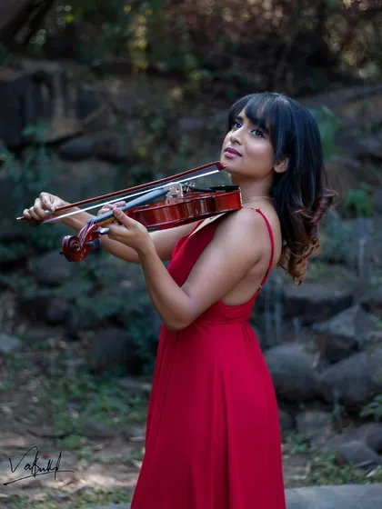 A beautiful portrait of the violinist in her element. The focus is on her connection with the instrument, set against a soft, natural background that enhances the serene mood of the photograph.