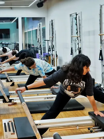 Clients perform a side stretch on the reformer, an excellent move for lengthening the side body and improving spinal mobility.