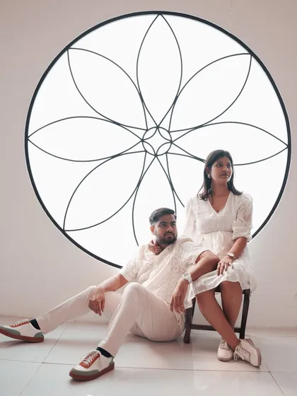 A stylish, high-fashion pose against a minimalist white backdrop with an artistic floral motif. This shot is perfect for couples who want a modern and artistic feel for their pre-wedding photos.