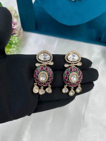 A close-up of another pair of kundan earrings with red meenakari.
