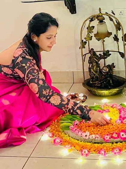 A client celebrating Diwali with a beautiful floral rangoli, wearing a custom printed blouse.