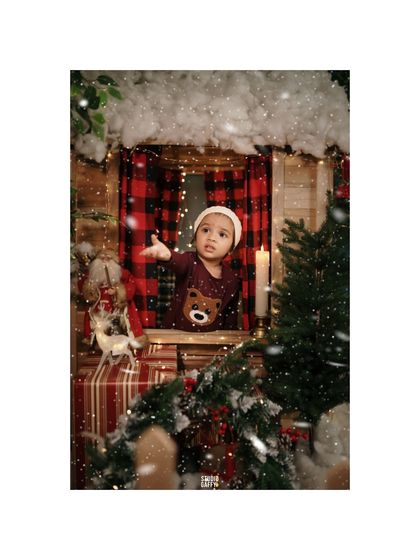 A baby peeking out of the window of our snowy Christmas cabin, watching the magic of the holidays unfold.