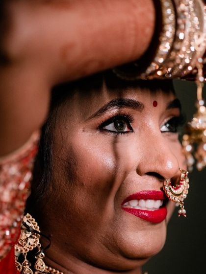 A candid moment of a North Indian bride during the ceremony, her expression full of emotion as she holds her hands up.