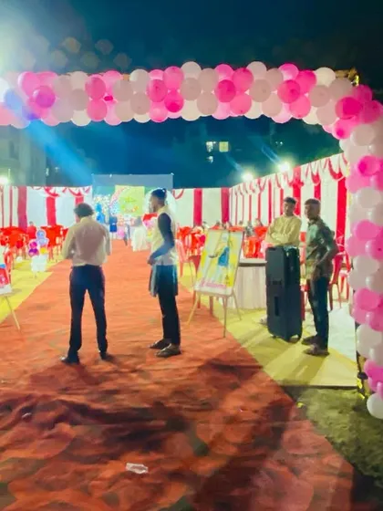 The entrance to a naming ceremony, marked by a pink and white balloon arch and a welcome sign.