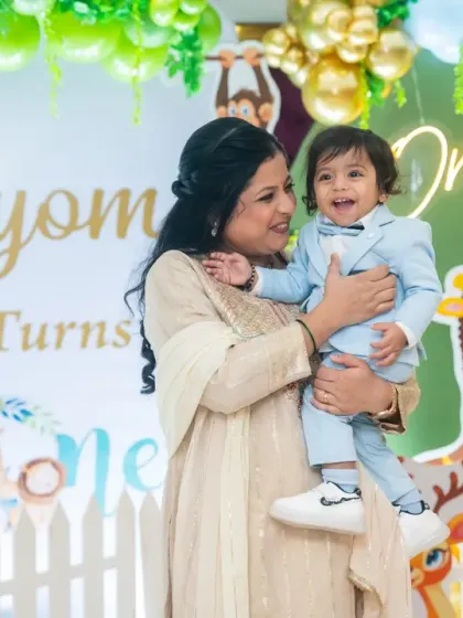 A sweet mother and son moment captured in front of the jungle-themed birthday party backdrop.
