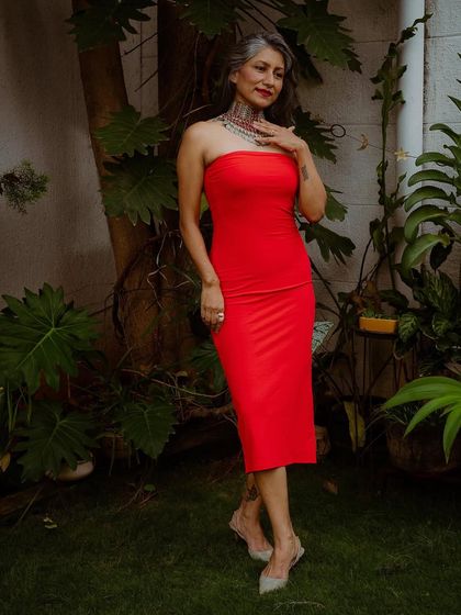 I believe in redefining beauty standards by embracing my silver hair. Here, I've paired a simple, bold red dress with a statement Afghani choker to create a powerful look.
