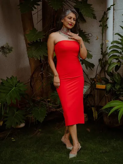 I believe in redefining beauty standards by embracing my silver hair. Here, I've paired a simple, bold red dress with a statement Afghani choker to create a powerful look.