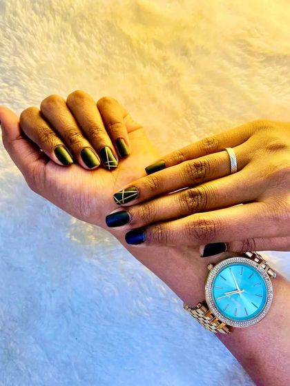 A stunning photo from a client showing off her gel nails with black polish and gold line detailing.