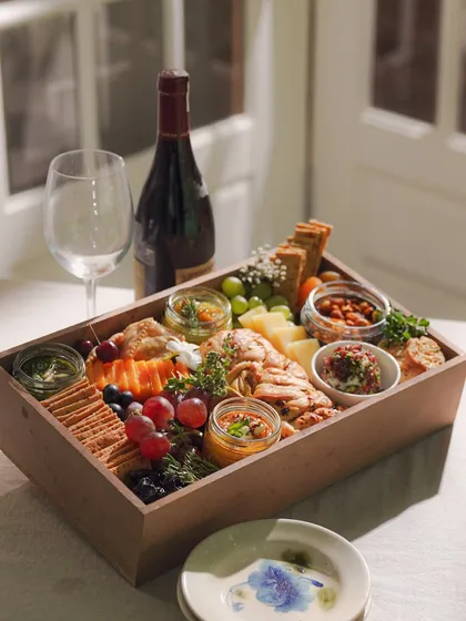 Our grazing box paired with a bottle of red wine, creating the perfect setup for a sophisticated evening in. It’s an ideal solution for effortless entertaining or a romantic night for two.