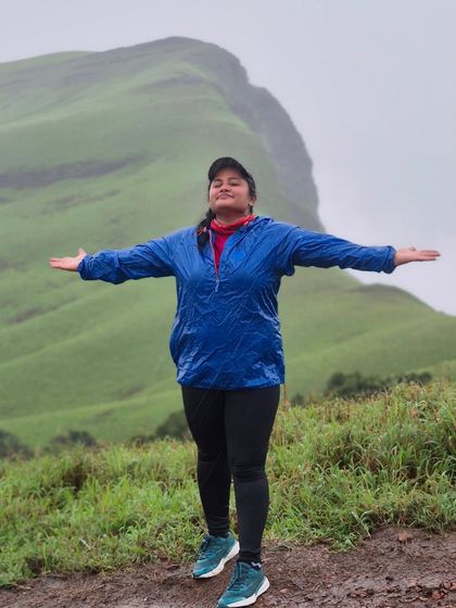 A trekker with arms wide open, feeling the freedom of the mountains on the Netravathi trail.