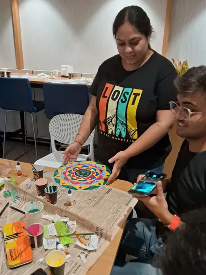 A student proudly displays her finished Lippan art piece during a corporate workshop. These sessions are a great way for teams to unwind and do something creative together.