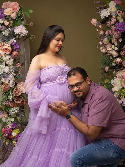 A tender moment between partners, framed by a beautiful floral arch. The father-to-be listens closely, connecting with his baby girl on the way.