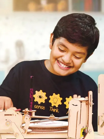 The smile of a maker! This student is proudly working with one of our custom-designed wooden robot kits. We create these kits to be engaging and accessible, allowing kids to understand mechanical and electronic principles through hands-on assembly.