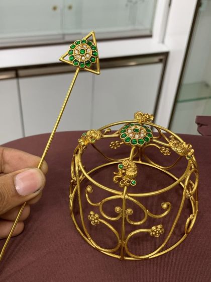 A closer look at the designer bun cover, showing the intricate gold-plated frame and the beautiful green stone and pearl embellishments.