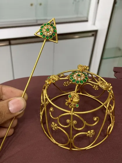 A closer look at the designer bun cover, showing the intricate gold-plated frame and the beautiful green stone and pearl embellishments.