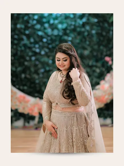 A candid-style portrait of Ishita, looking down with a soft smile, against a backdrop of floral decor.