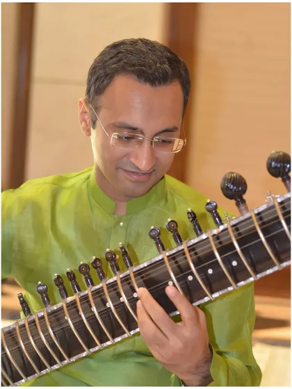 A close-up in a green kurta, playing Raag Shahana.