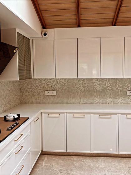This shot focuses on the clean lines of the handle-less upper cabinets and the contrast with the textured backsplash and wooden ceiling detail, adding layers of visual interest.