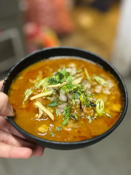 Holding up a bowl of our authentic Nalli Nihari. It's a dish we are incredibly proud of, representing generations of culinary tradition.