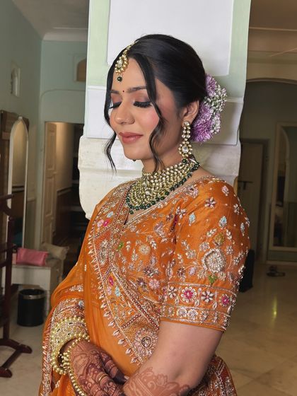 A side profile of the bride, showing how the floral bun and face-framing tendrils create a soft and romantic silhouette. This is a perfect angle to appreciate the complete bridal hair and makeup.