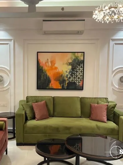 A closer look at the vibrant living room, highlighting the plush olive green sofa and the elegant wall molding. The abstract artwork adds a splash of color, tying the room's palette together.