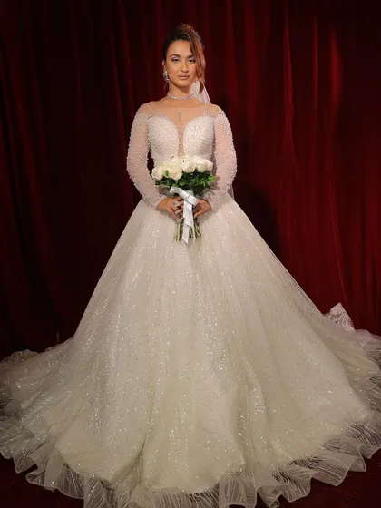 Holding her bouquet, this bride is the picture of perfection. The entire look, from the gown to the makeup, is a seamless blend of grace and style.