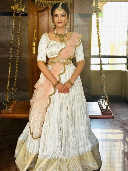 A full-length shot of the bride in her beautiful white and peach half-saree, perfect for a daytime wedding event.