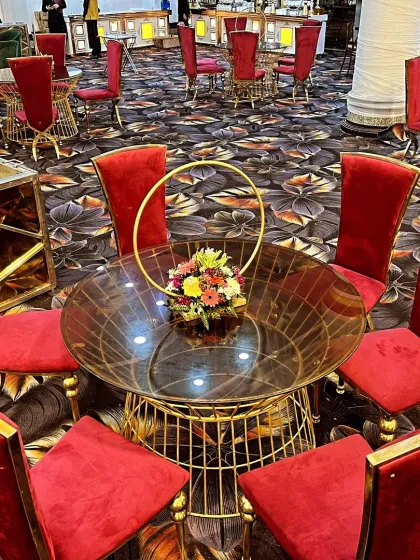 This round table seating arrangement uses high-back red velvet chairs. The gold wire-frame table and floral centerpiece match the other seating clusters for a cohesive look.