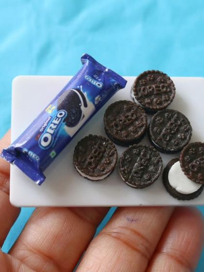 A miniature packet of Oreo biscuits, with a few cookies out on a plate.