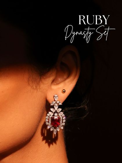 A close-up of the Ruby Dynasty earring, highlighting the regal brilliance of the central ruby framed by a halo of sparkling diamonds.