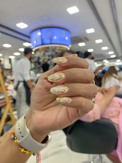 The final result of an airbrush and chrome nail set. This design features a white base with gold chrome swirls for an elegant and artistic look.