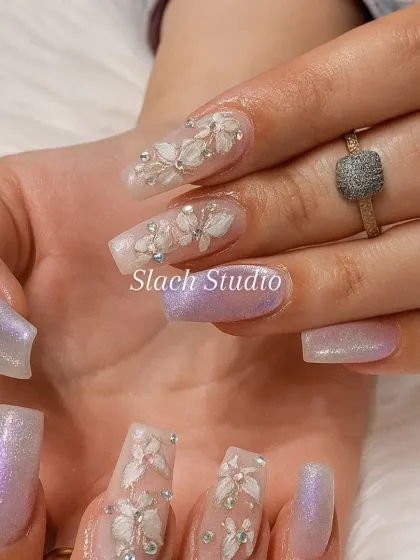 A different angle of the 3D floral and shimmer nail set, highlighting the craftsmanship of the sculpted flowers on the translucent extension base.