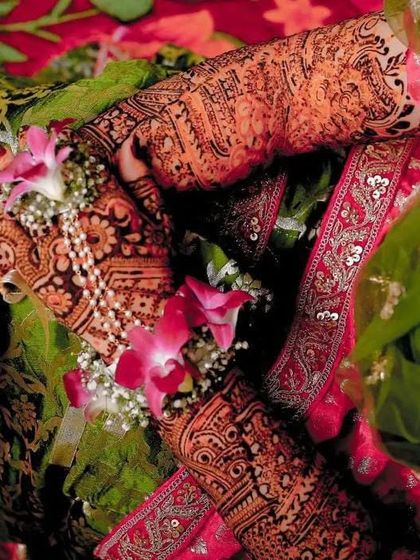A candid shot capturing the beauty of the dark henna stain amidst the vibrant colors and flowers of a wedding ceremony.