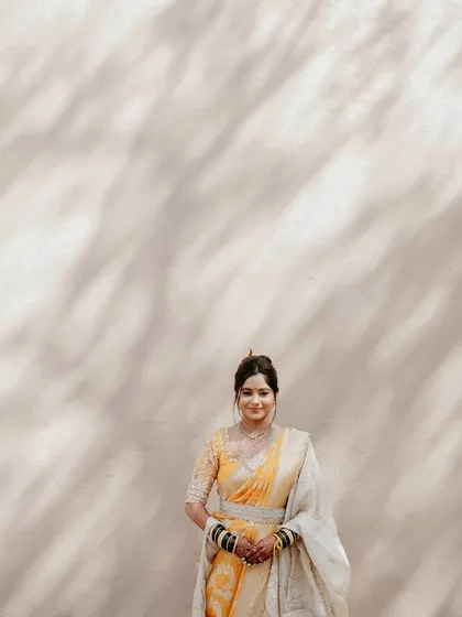A full view of the bride, showcasing the beautiful drape of her saree and the natural, glowing makeup.