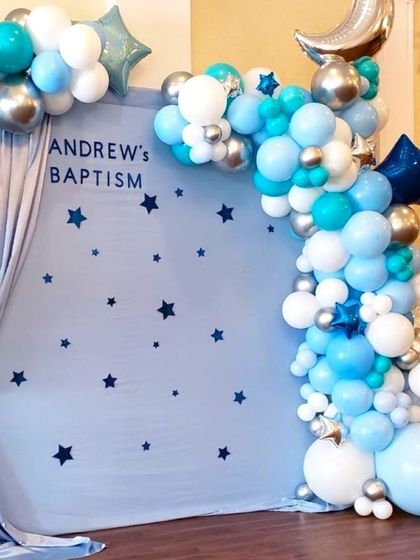 A simple balloon decoration for a baptism. The backdrop features a star theme and is framed by a blue, white, and silver balloon arrangement.