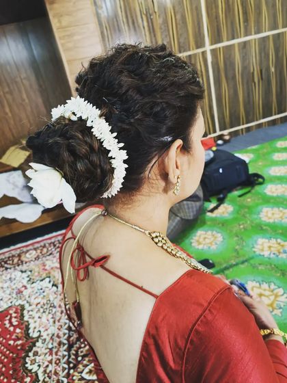 A classic bridal bun adorned with a traditional gajra of white flowers. This hairstyle is perfect for securing a dupatta and complements a traditional saree or lehenga beautifully.