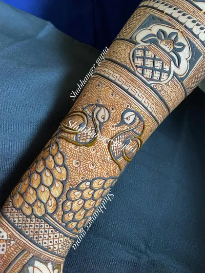 A close-up of a bridal arm design showing two peacocks facing each other. This is a romantic and symbolic representation of the couple.