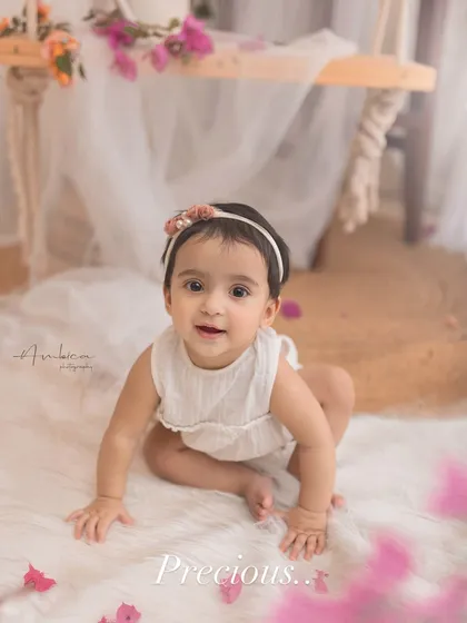 A precious moment from a spring-themed sitter session. This baby is crawling on a soft white rug, surrounded by beautiful bougainvillea flowers.