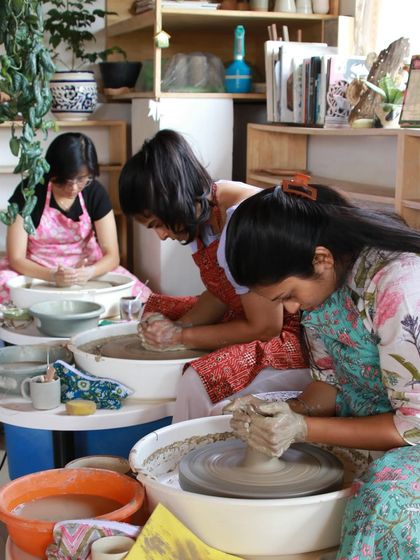 A group of students works diligently at their pottery wheels, capturing the focused and creative atmosphere of our weekend courses.