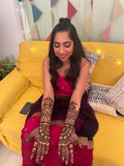 A full view of the bride on a bright yellow sofa, displaying her completed mehndi.