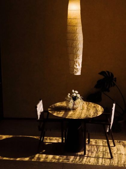 A small dining table catches the golden hour light, creating an intimate and warm spot for a private meal or a cup of tea.