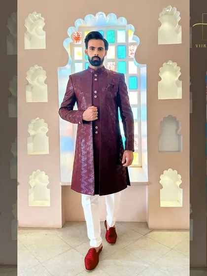 The full look of the maroon sherwani, paired with white trousers and red loafers for a complete, coordinated groom's outfit.
