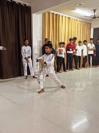 Young students in their martial arts uniforms demonstrating their stances. They are learning discipline and focus, lining up to perform their forms.