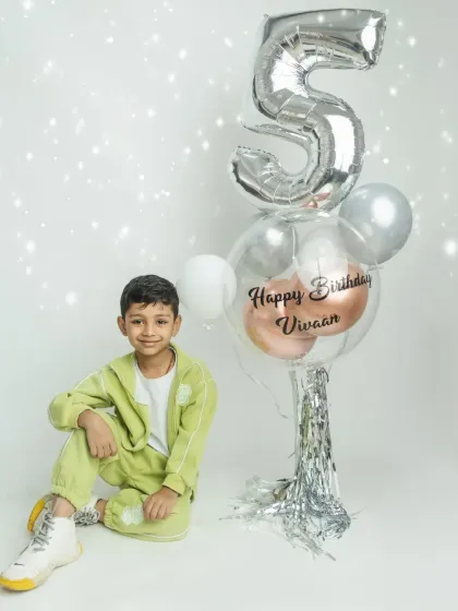 A cool and casual pose from the birthday boy, celebrating turning five with a stylish balloon setup.